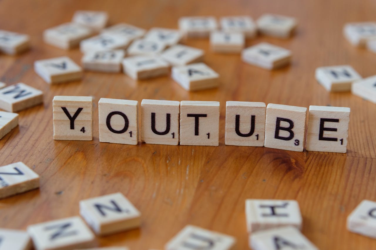 Wooden letter tiles spelling YOUTUBE on a wooden surface, symbolizing video sharing and streaming.